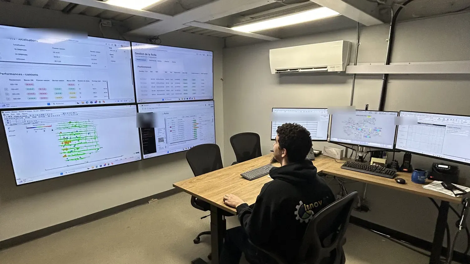 Salle d’optimisation des opérations conçue par InnovAS Global : opérateur devant un mur d’écrans de suivi de flotte